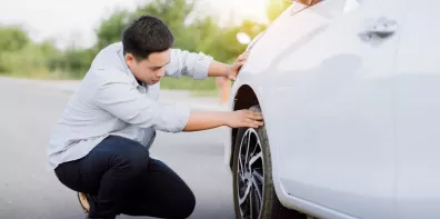 homme qui vérifie ses pneus de voiture